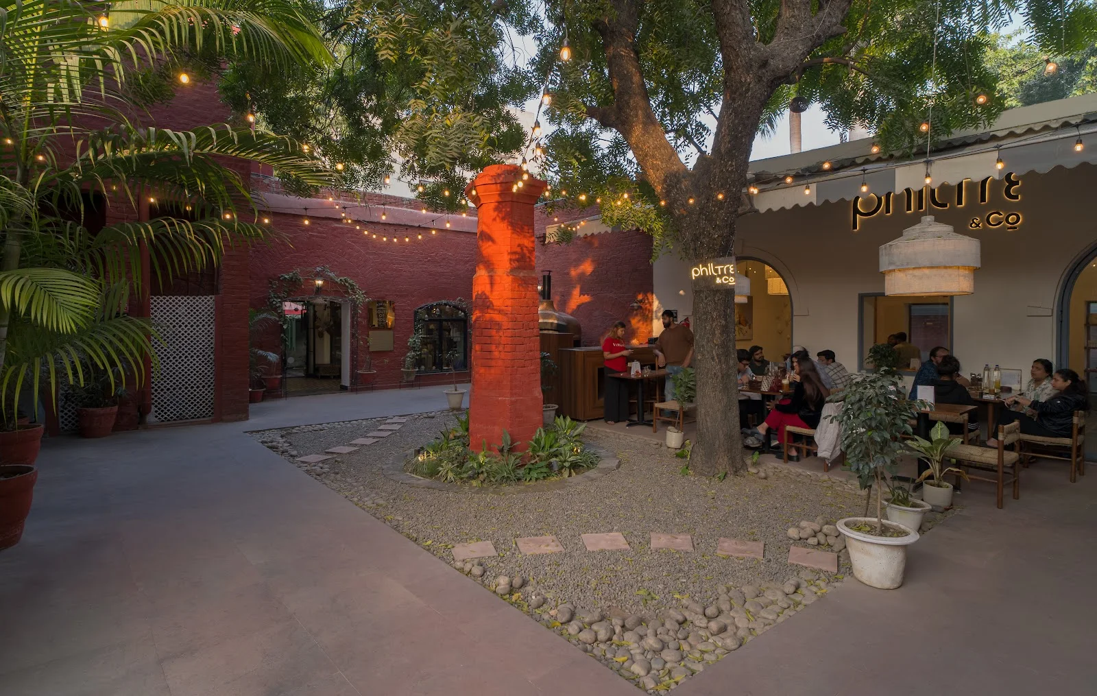 A tree-shaded Le Press courtyard with a red sculpture
